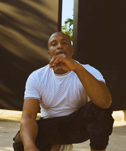 Dialect Sosa seated outside in a white shirt